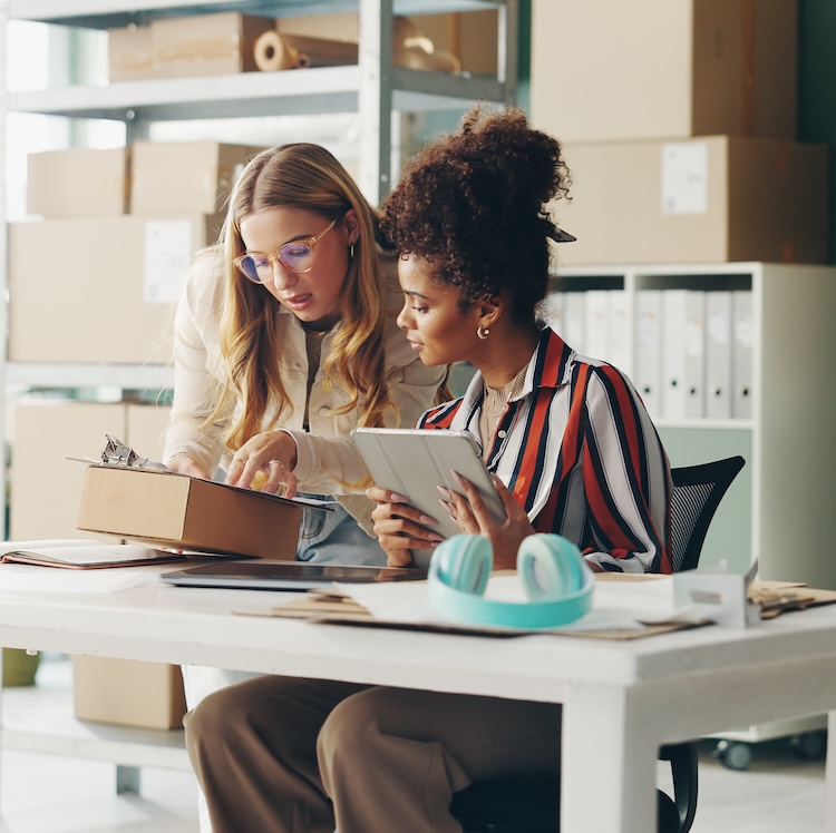 Women, tablet and teamwork for office logistics, package and e commerce checklist with stock of online shop. Small business people or seller with digital tech, box and clipboard for website order